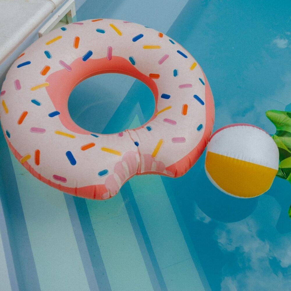 A vibrant display of fun pool floats and beach ball in a clear swimming pool.