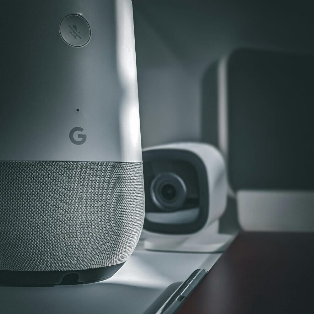 Close-up of smart home devices, showcasing a modern speaker and camera setup in a minimalist style.