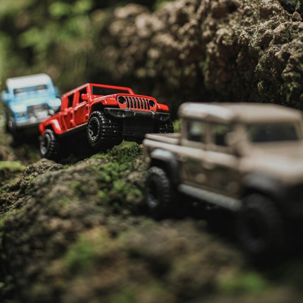 Toy jeeps climbing moss-covered rocks, depicting a rugged off-road adventure scene.