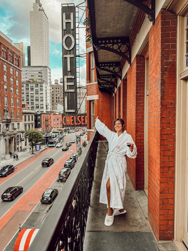 Woman in a bathrobe enjoying the view from a Hotel Chelsea balcony in New York City.